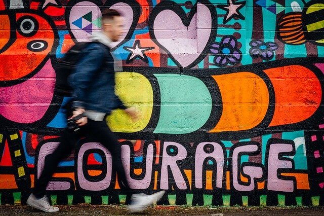 man walking past colorful mural